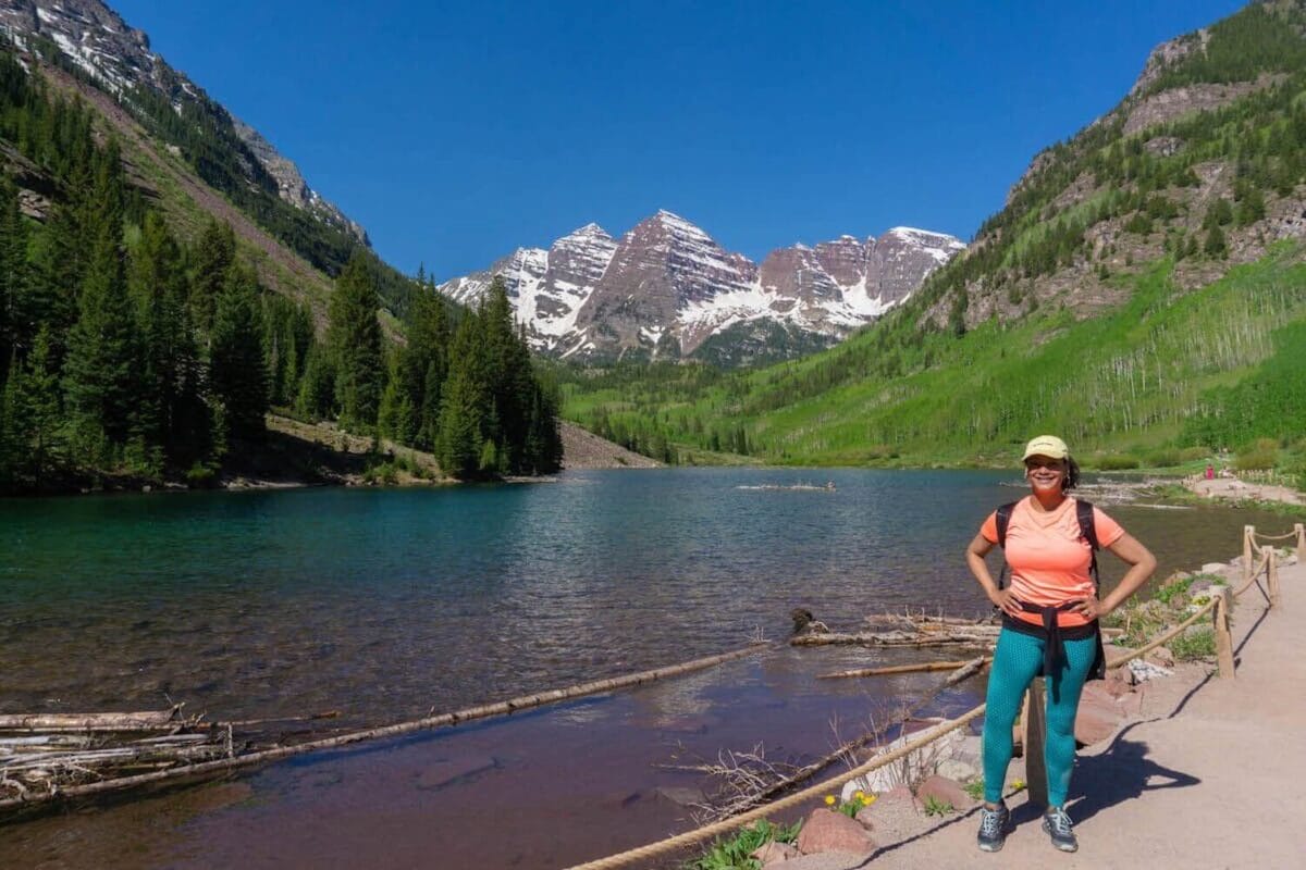 Hiker standing in front of snowcapped mountains and alpine lake